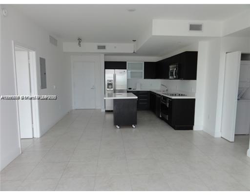 A modern kitchen with dark cabinets and a mobile island sits in an open-plan room — 90 SW 3rd St # 2907, Miami FL 33130, MIAMI, FL