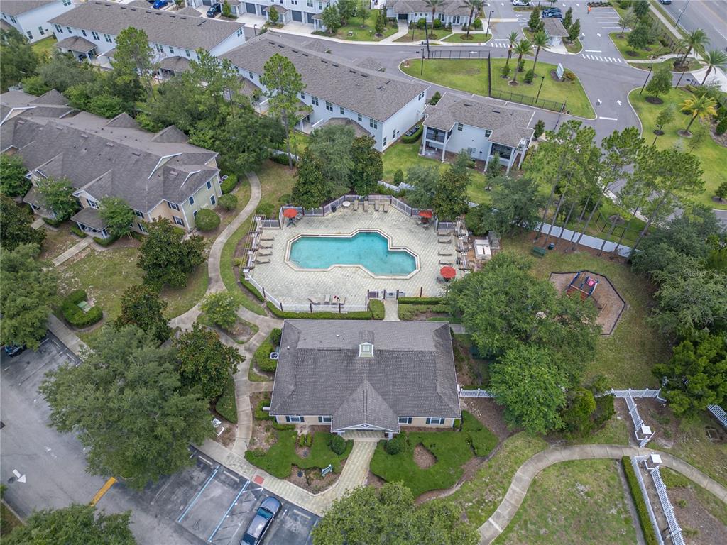An aerial view shows a community clubhouse, swimming pool, and playground surrounded by apartment buildings — 930 MOONLIGHT COVE ROAD UNIT 11-107, ORANGE CITY, FL