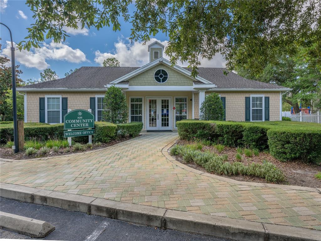 A paved walkway leads to the entrance of a single-story community center building — 930 MOONLIGHT COVE ROAD UNIT 11-107, ORANGE CITY, FL