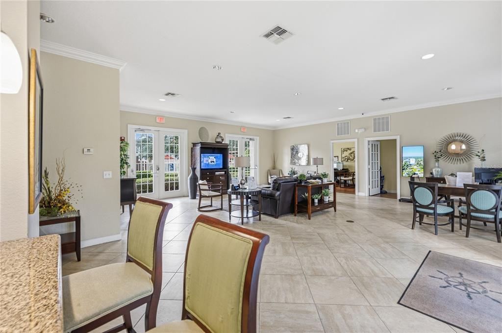 A spacious community clubhouse room features tile flooring, a seating area, and dining tables — 930 MOONLIGHT COVE ROAD UNIT 11-107, ORANGE CITY, FL