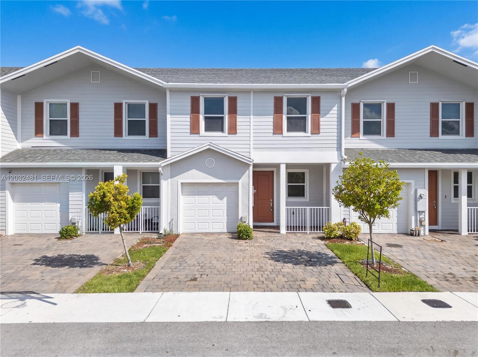 A row of three light-gray townhouses features brick paver driveways and small front trees — 1780 SE 9th Ave, Homestead FL 33034, HOMESTEAD, FL