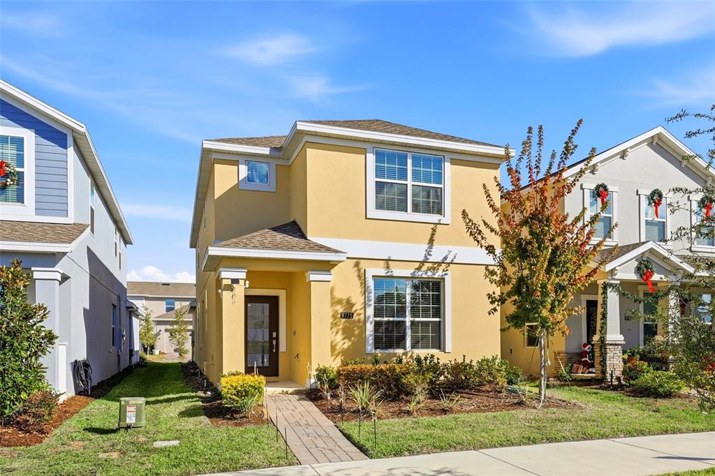 A yellow two-story suburban house with a front walkway and a small landscaped yard — 9775 INTRODUCTION WAY, ORLANDO, FL