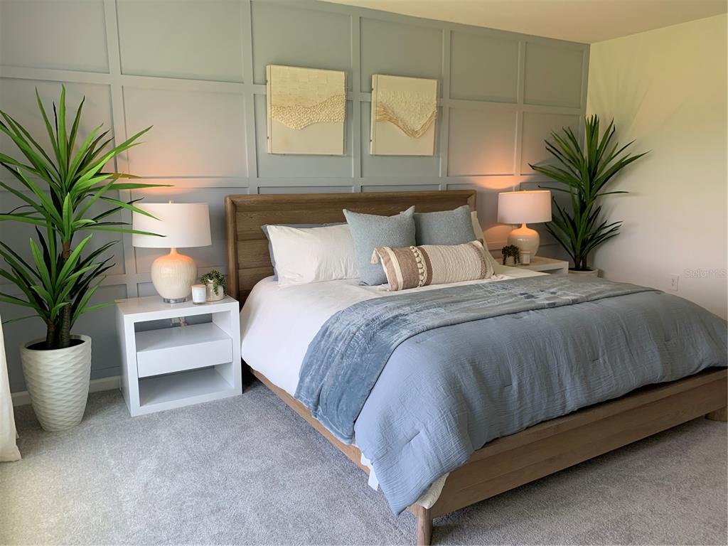 A bedroom features a wood bed frame, blue bedding, and a paneled accent wall — 5228 WORCHESTER DRIVE, KISSIMMEE, FL