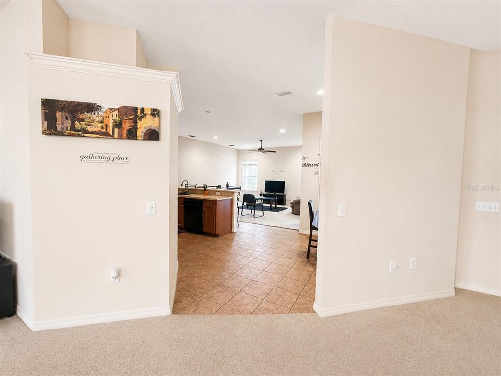 A view from a carpeted room looking into a tiled kitchen and living area — 5635 CANVASBACK COURT, LAKELAND, FL