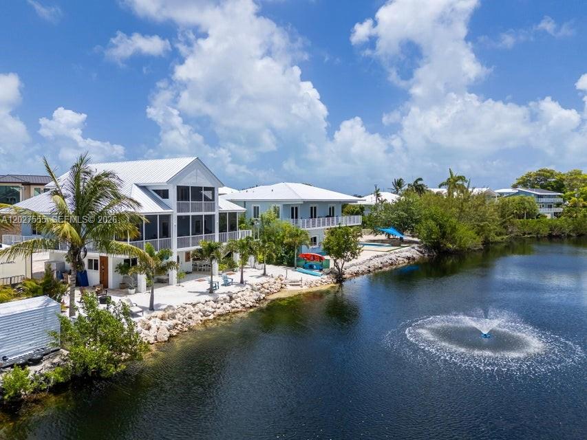 An aerial view shows two white houses situated along a waterfront with a fountain — KEY LARGO, FL