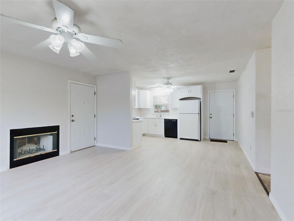 An open-concept living and dining area features light wood floors, white walls, and ceiling fans — 111 VALENCIA DRIVE, EDGEWATER, FL