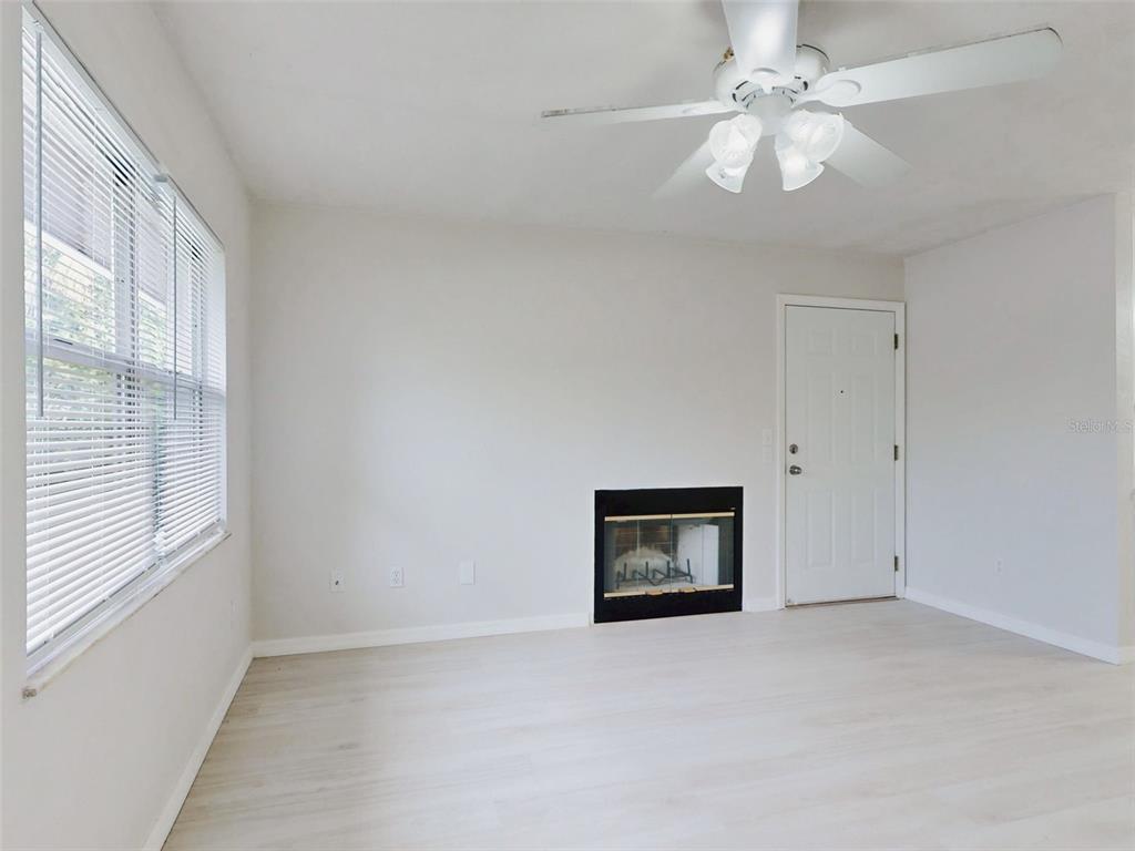 A bright, empty room features light wood-look flooring, white walls, a window, and a ceiling fan — 111 VALENCIA DRIVE, EDGEWATER, FL