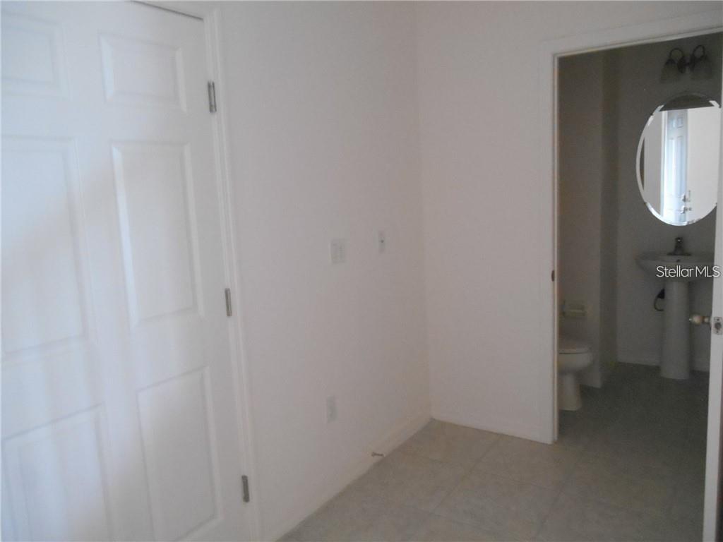 A white room with a closed door and an open doorway leading to a bathroom — 6344 CAMINO DRIVE, APOLLO BEACH, FL