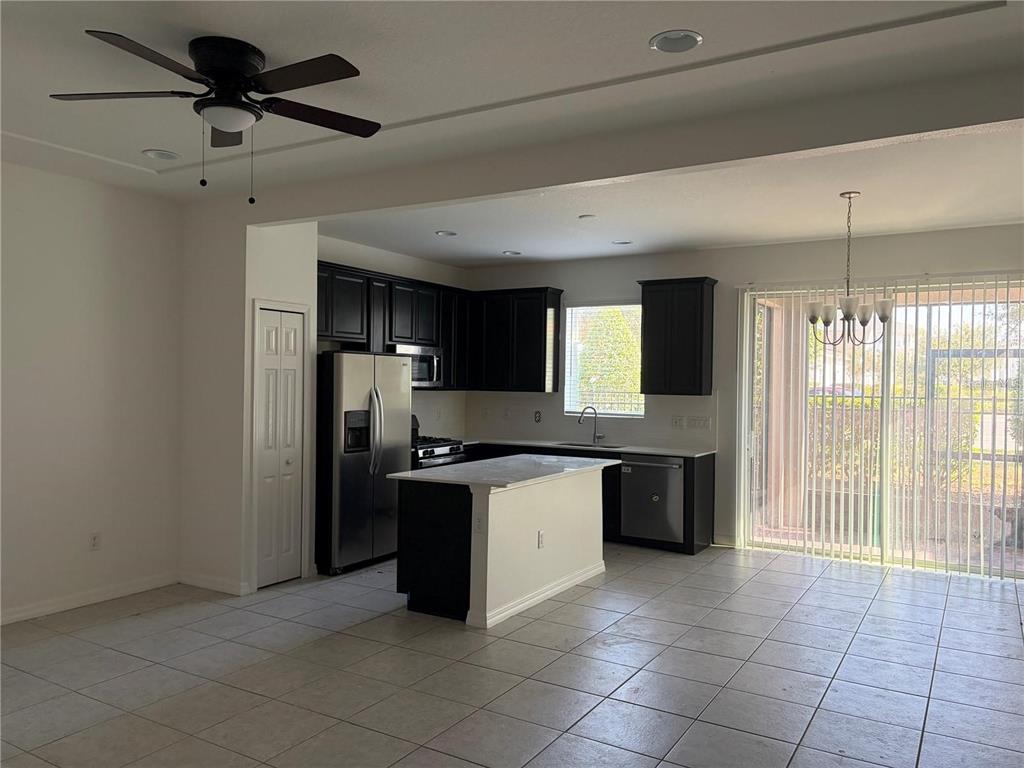 A kitchen with dark cabinets, a white island, and tile flooring opens to a patio — 6344 CAMINO DRIVE, APOLLO BEACH, FL