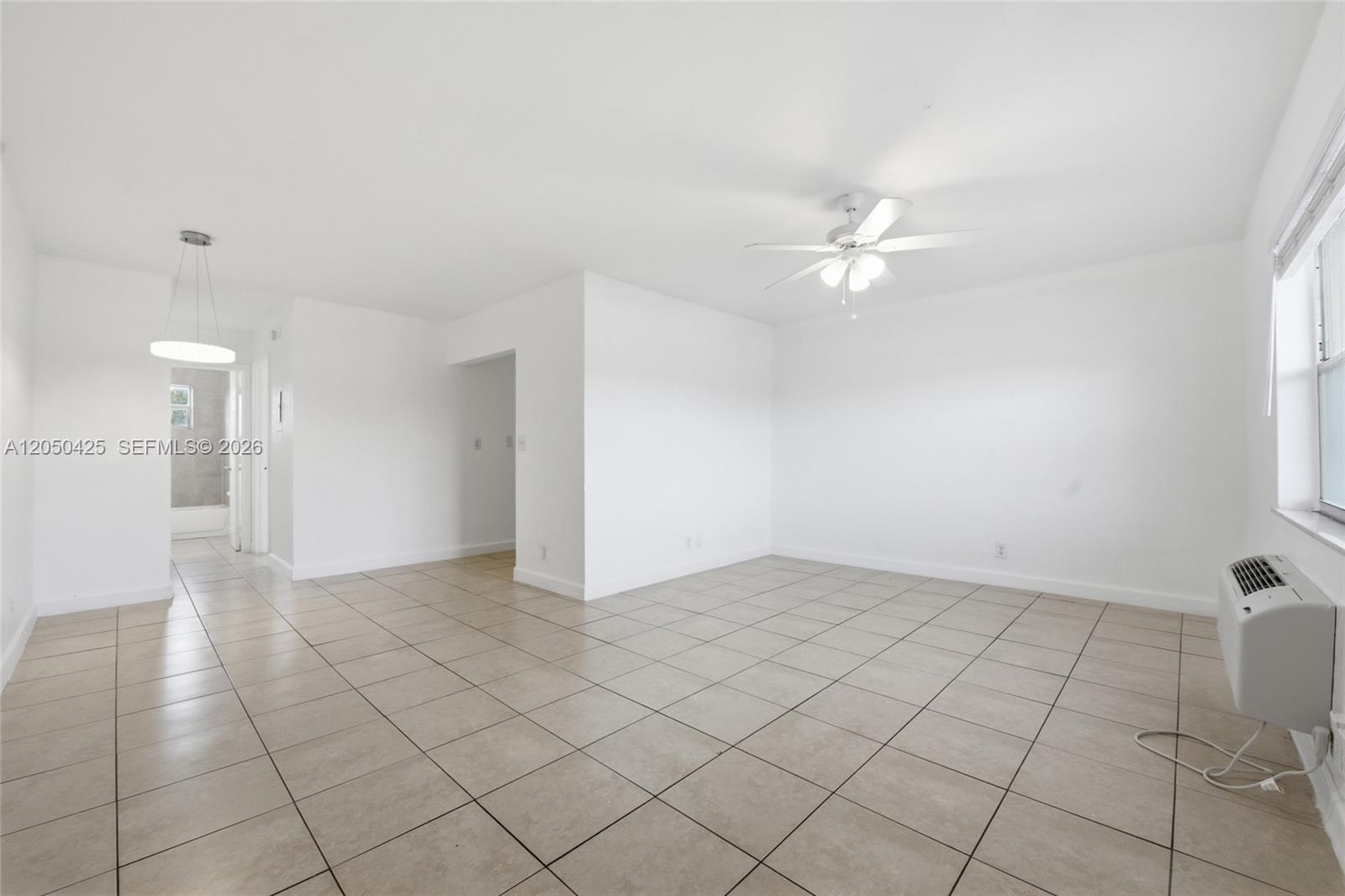 An empty room with white walls, tiled floors, a ceiling fan, and a window unit — MIRAMAR, FL