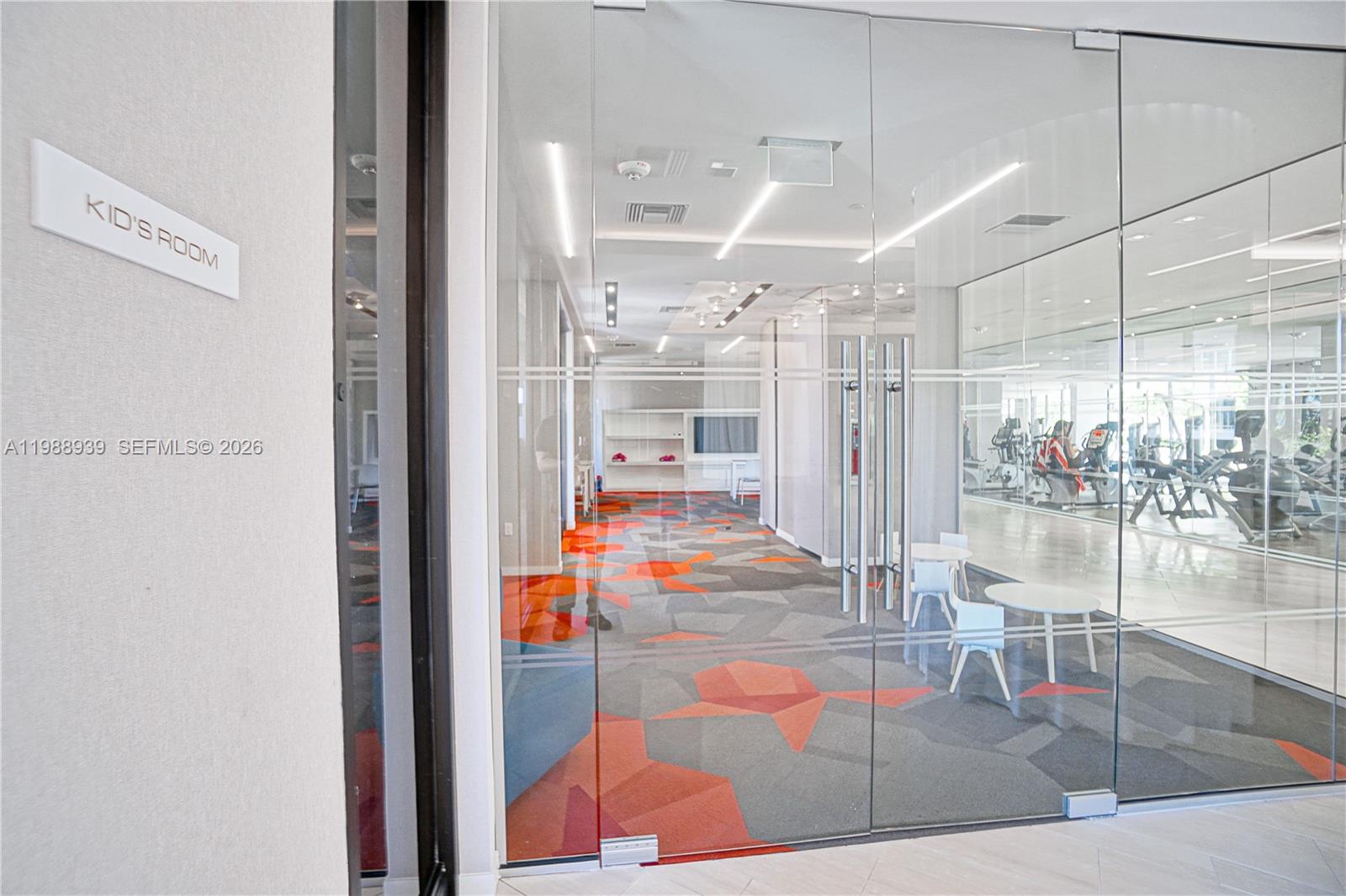 A glass-walled kid's room features a geometric patterned carpet and small white tables — 9 Island Ave # 2410, Miami Beach FL 33139, MIAMI BEACH, FL