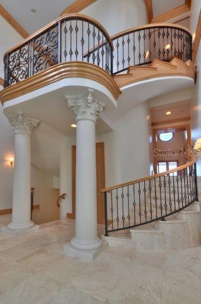 A grand foyer features a curved staircase with wrought iron railings and two classical columns — 220 GULF BOULEVARD UNIT 8, BELLEAIR BEACH, FL
