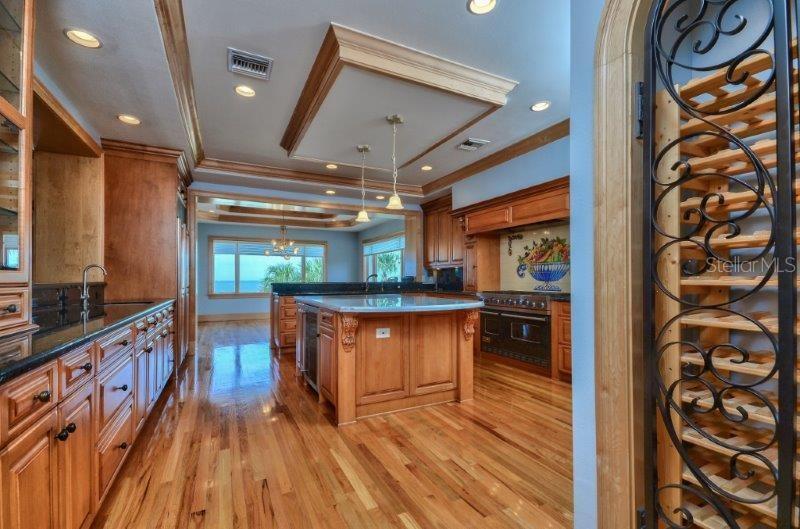 A kitchen with wood cabinets, a central island, and a wine rack in the foreground — 220 GULF BOULEVARD UNIT 8, BELLEAIR BEACH, FL