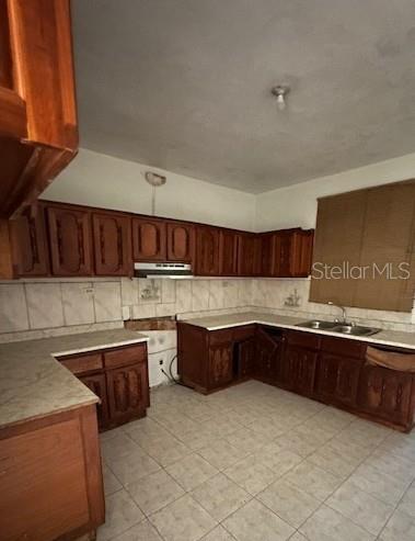 A kitchen with wooden cabinets, tiled floors, and a double sink under a window — Carr. 635 Lote 1 BO. AIBONITO, HATILLO, PR