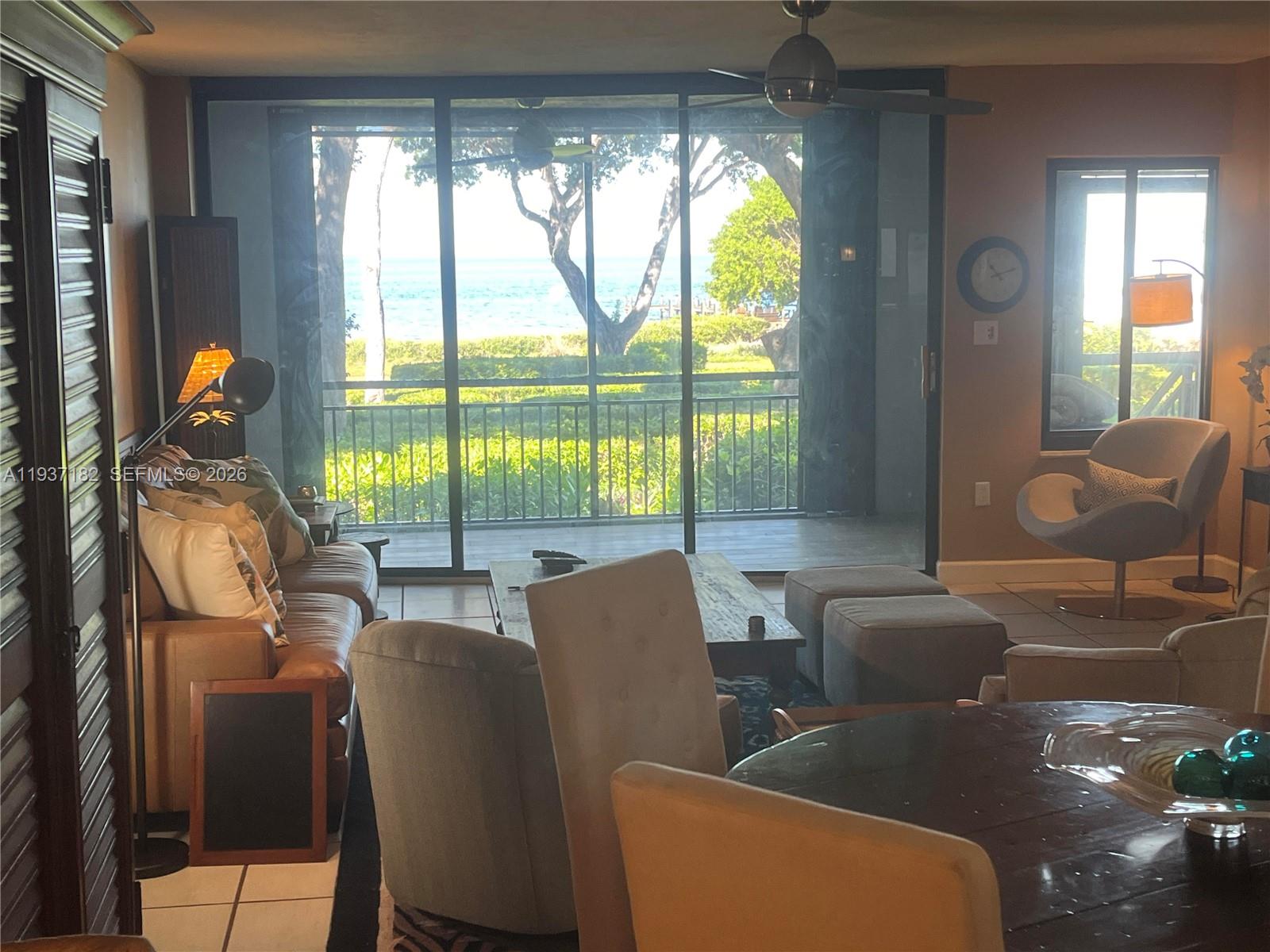 A living room features a large sliding glass door overlooking a balcony and the ocean — 202 Sanctuary Dr, Key Largo FL 33037, KEY LARGO, FL