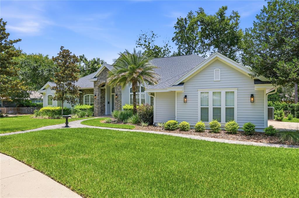 A light-colored, single-story house with a stone entryway, palm tree, and manicured lawn — 5117 NW 55TH STREET, GAINESVILLE, FL