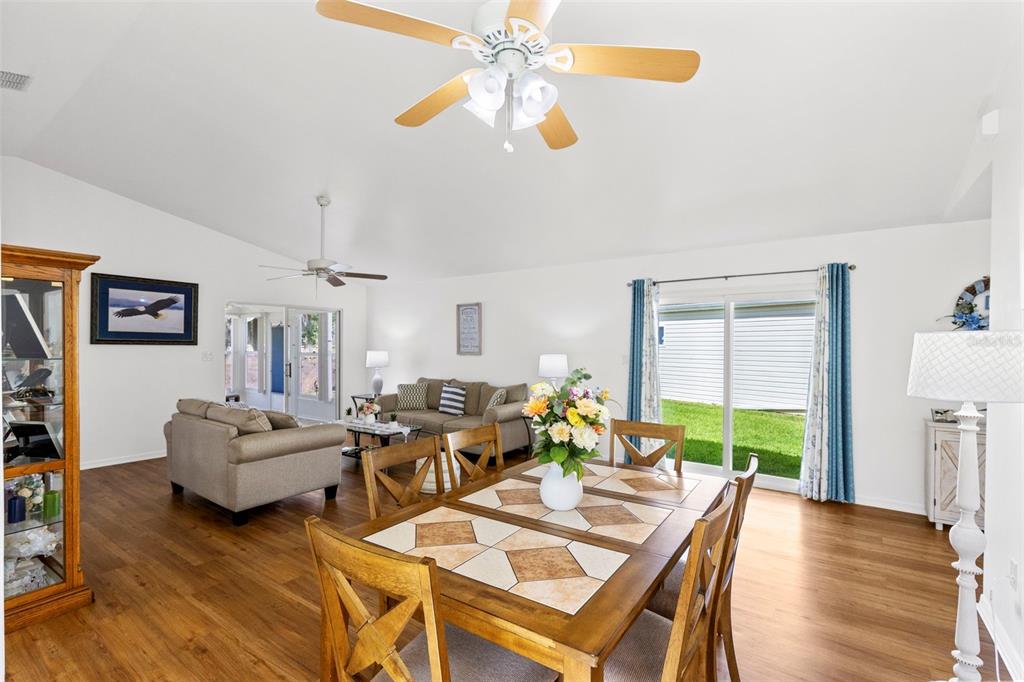 A dining area with a tiled table sits in the foreground of an open-concept living room — 4960 HERON RUN CIRCLE, LEESBURG, FL