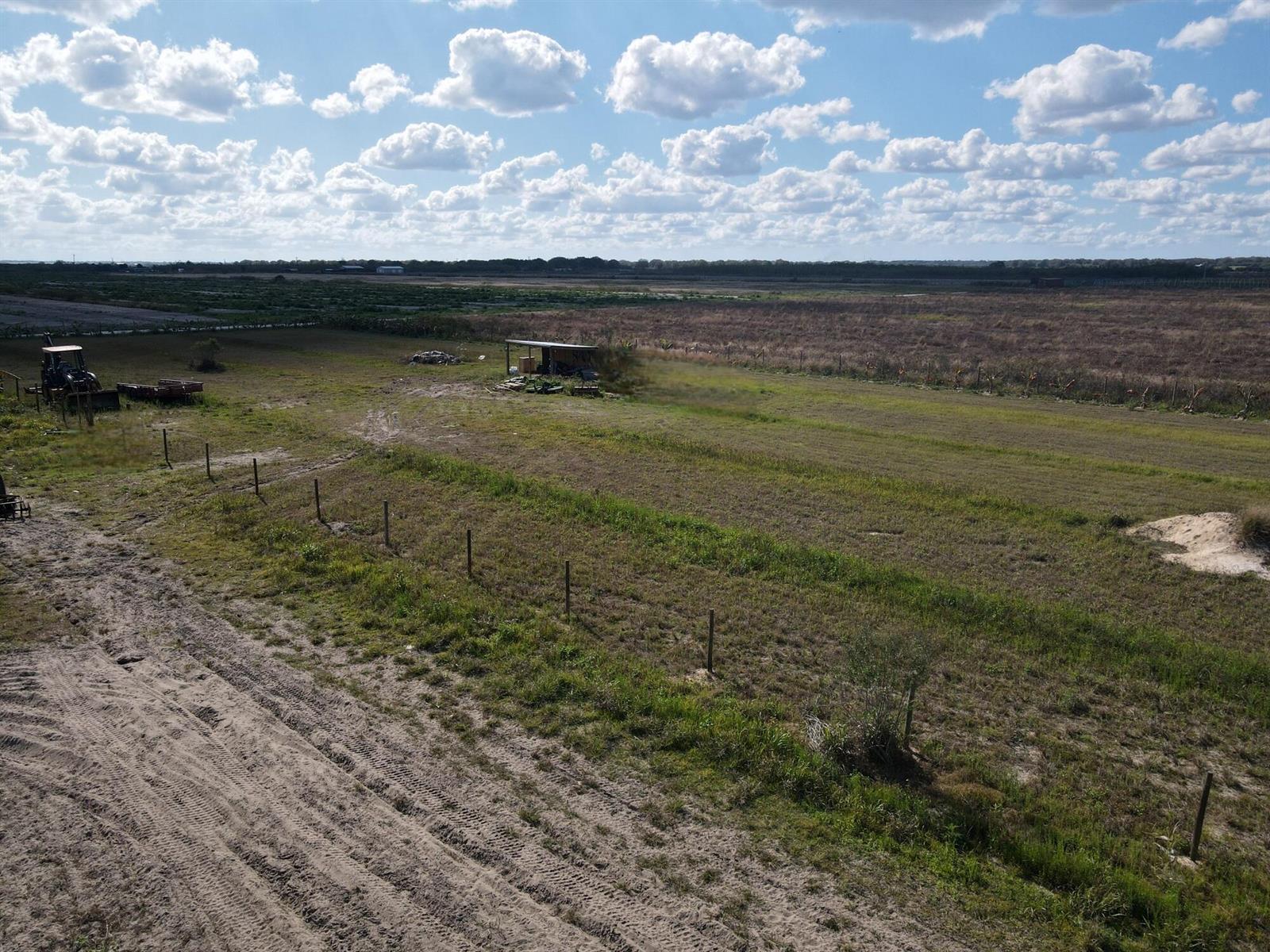 An aerial view of a large, grassy rural field with a fence and a small shed — 6694 5th Road, FL 33935, FL