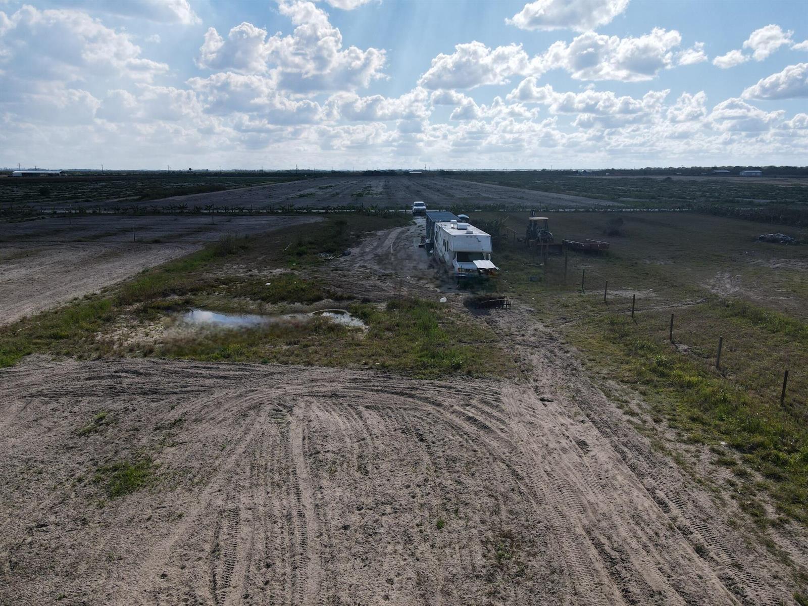 An aerial view shows a recreational vehicle parked on a large, flat, rural dirt lot — 6694 5th Road, FL 33935, FL