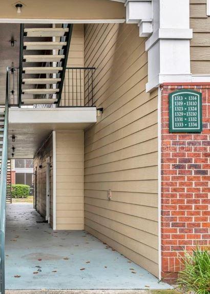 An exterior view of an apartment building breezeway with stairs and a unit number sign — 13003 PLANTATION PARK CIRCLE UNIT 1319, ORLANDO, FL