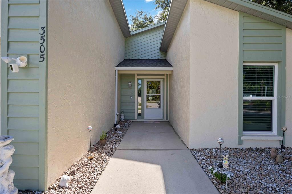 The exterior view shows a concrete walkway leading to a front door with light-colored siding — 3505 45TH STREET W, BRADENTON, FL
