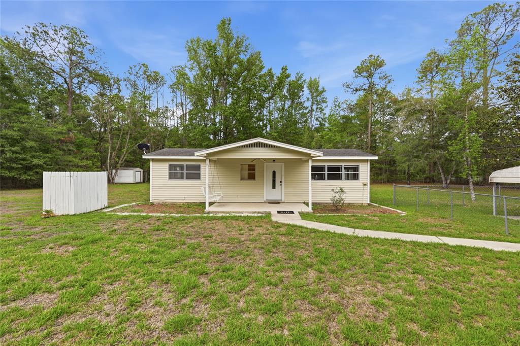 A single-story house with light yellow siding, a front porch, and a surrounding grassy yard — 16913 NE 77TH LANE, HAWTHORNE, FL
