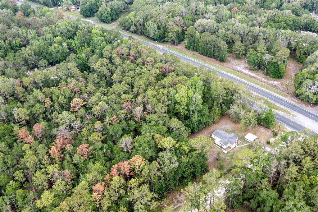 An aerial view shows a house surrounded by dense forest next to a paved road — 16913 NE 77TH LANE, HAWTHORNE, FL