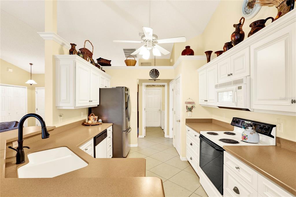 A kitchen features white cabinets, tan countertops, a black refrigerator, and a white stove — 4721 TARA VIEW ROAD, LEESBURG, FL