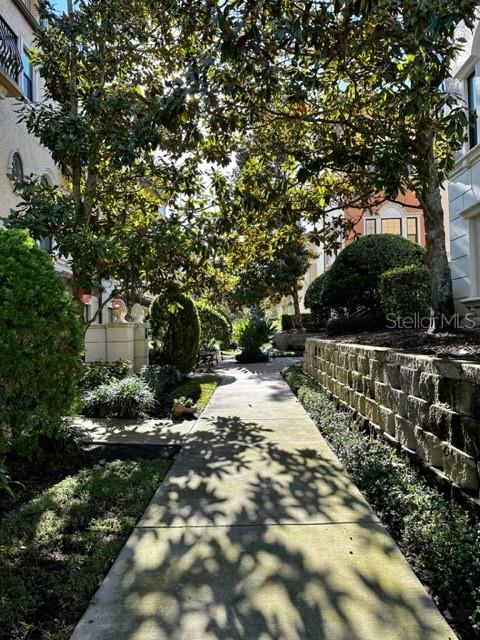 A concrete walkway leads through a landscaped courtyard between two multi-story residential buildings — 4232 MESSINA DRIVE, LAKE MARY, FL