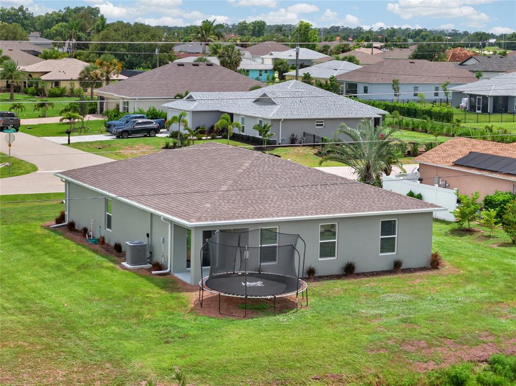 An aerial view of a gray suburban house with a backyard trampoline and lawn — 25138 ALICANTE DRIVE, PUNTA GORDA, FL