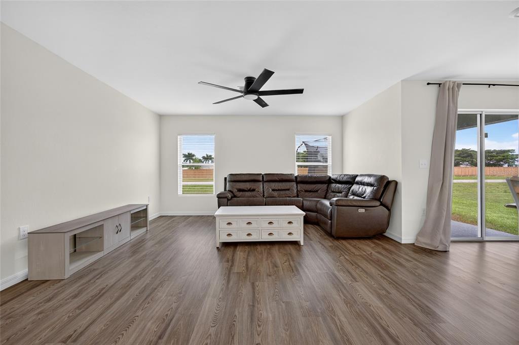 A living room with wood-look flooring, a brown sectional sofa, and a white coffee table — 25138 ALICANTE DRIVE, PUNTA GORDA, FL
