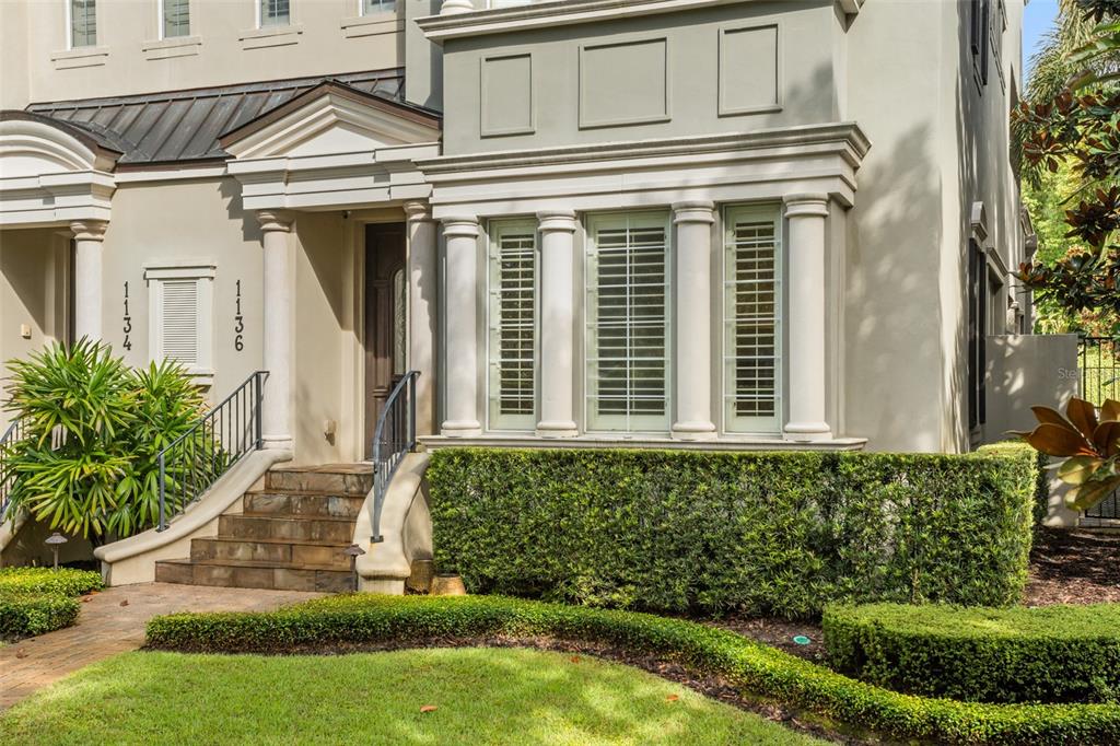 The exterior of a multi-story home features a stone staircase leading to a dark wood door — 1136 S PENNSYLVANIA AVENUE, WINTER PARK, FL