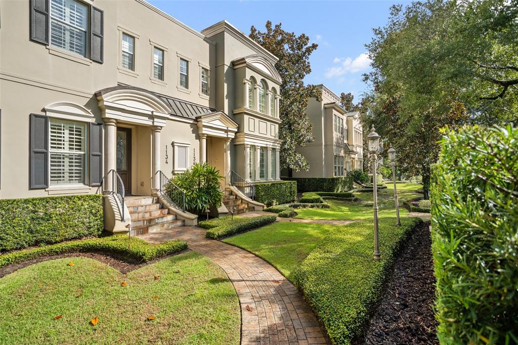 A brick walkway leads to the entrances of two adjacent beige townhouses with manicured landscaping — 1136 S PENNSYLVANIA AVENUE, WINTER PARK, FL