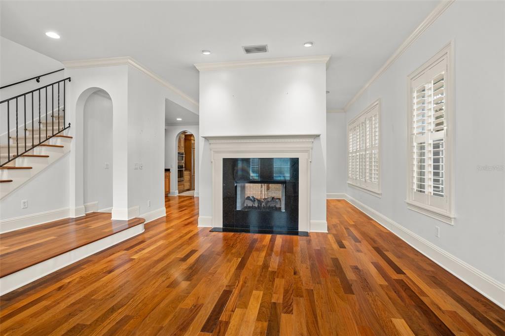A living room features hardwood floors, a central fireplace, and a staircase with iron railings — 1136 S PENNSYLVANIA AVENUE, WINTER PARK, FL
