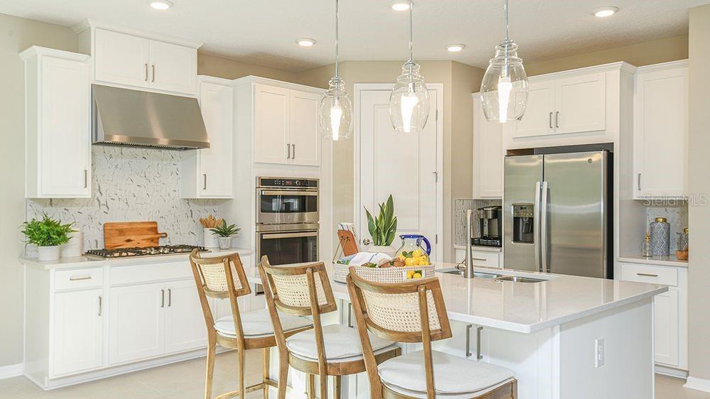 A modern kitchen features white cabinetry, stainless steel appliances, a marble backsplash, and a central island — 4 ARMENIA COURT, PALM COAST, FL
