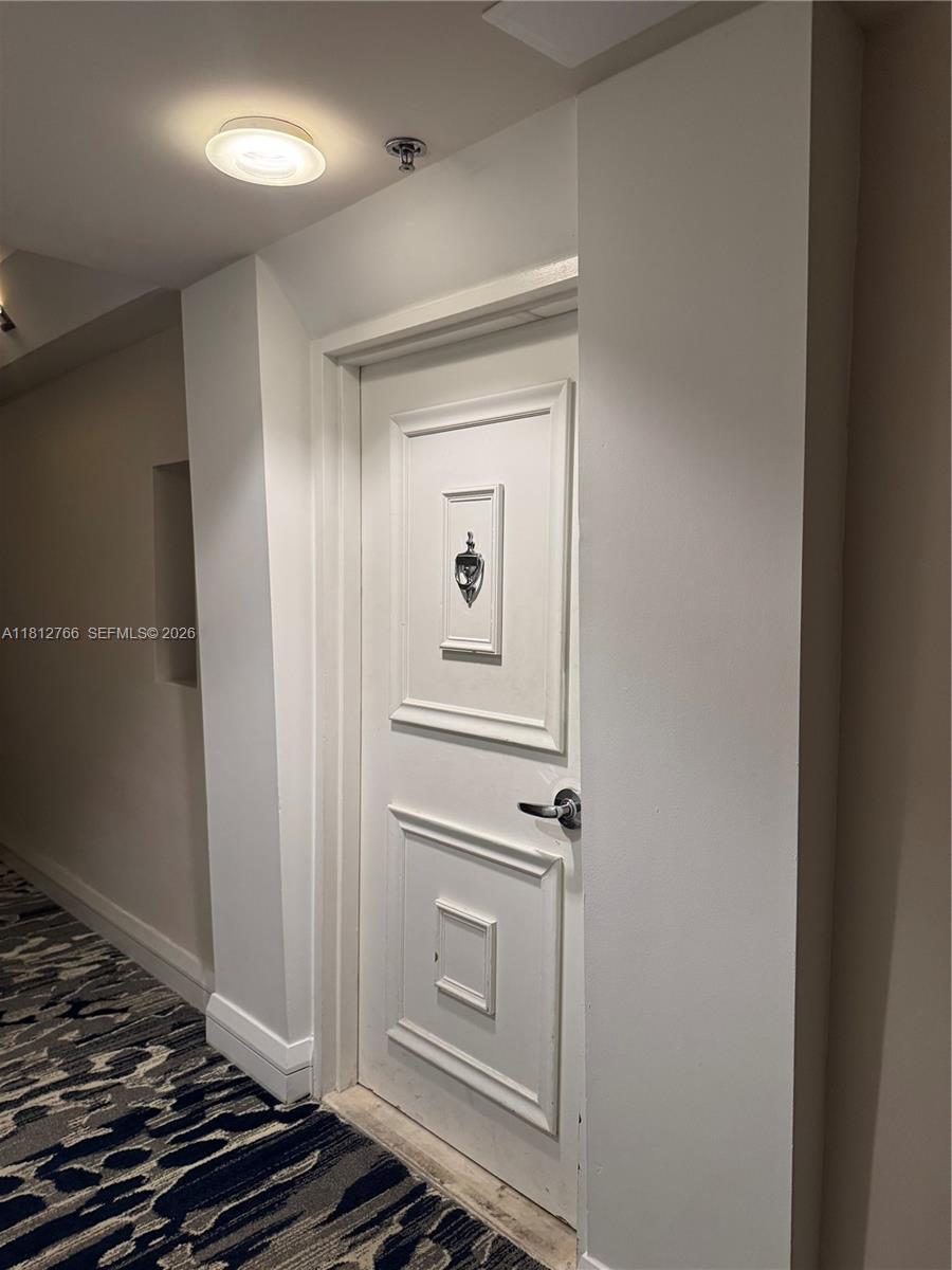 A white paneled door with a decorative knocker is situated in a carpeted hallway — 5161 Collins Ave # 315, Miami Beach FL 33140, MIAMI BEACH, FL