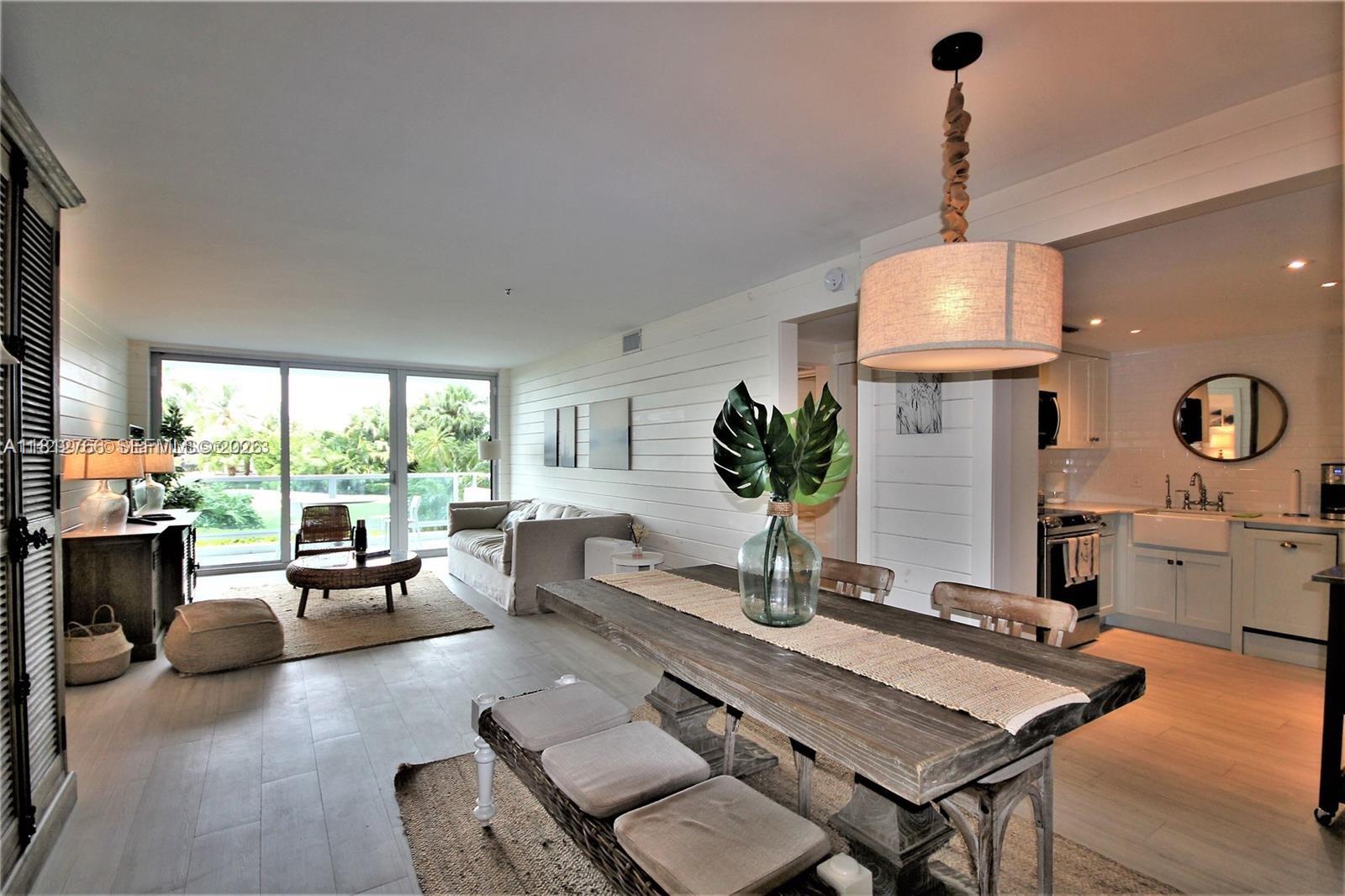 A dining area with a wooden table leads into a living room with shiplap walls — 5161 Collins Ave # 315, Miami Beach FL 33140, MIAMI BEACH, FL