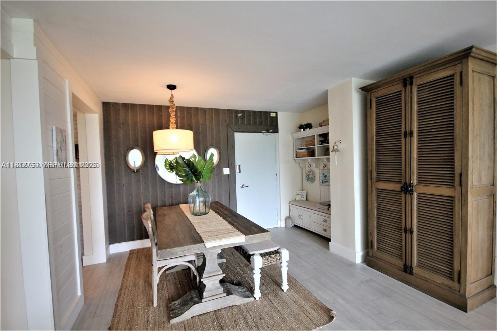 A dining area features a wooden table, a jute rug, and a large wooden armoire — 5161 Collins Ave # 315, Miami Beach FL 33140, MIAMI BEACH, FL