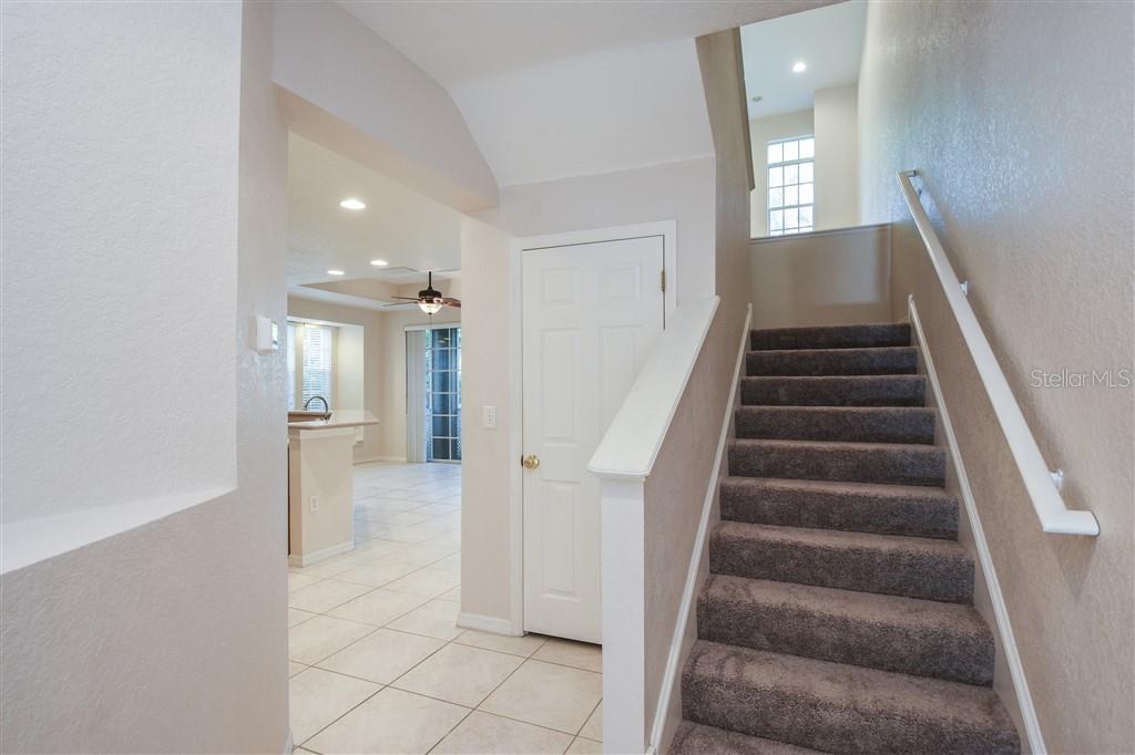 A carpeted staircase leads upward next to a white door and a tiled entryway — 1812 BAYSHORE WAY, CLEARWATER, FL