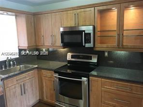 A kitchen features light wood cabinets, stainless steel appliances, and dark countertops — 3933 Adra Ave # 47, Doral FL 33178, DORAL, FL