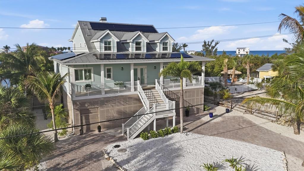 A light blue elevated house with a metal roof, solar panels, and a front staircase — 81 N GULF BOULEVARD, PLACIDA, FL