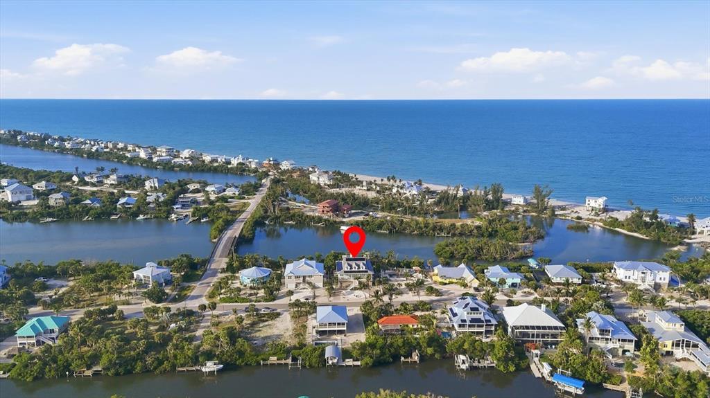 An aerial view shows a coastal neighborhood with houses situated between a bay and ocean — 81 N GULF BOULEVARD, PLACIDA, FL