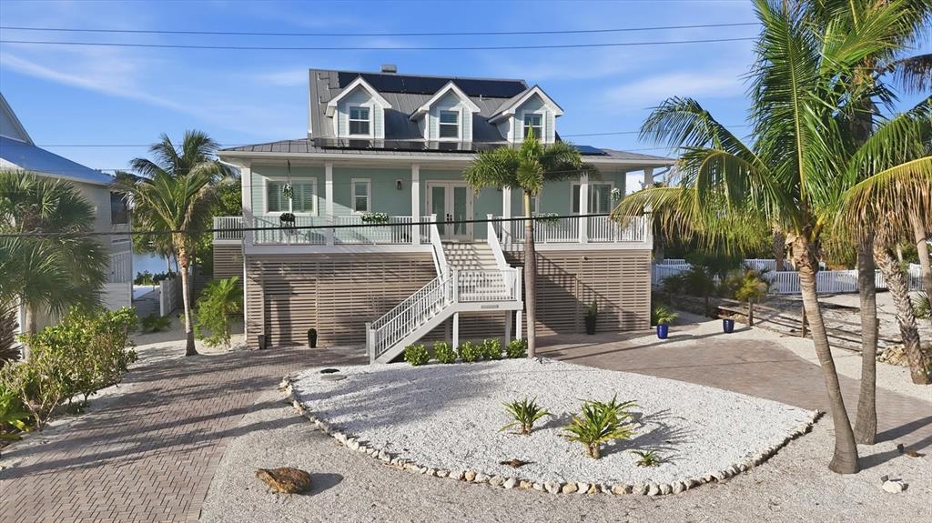 A light green elevated house with a metal roof, dormer windows, and a front staircase — 81 N GULF BOULEVARD, PLACIDA, FL