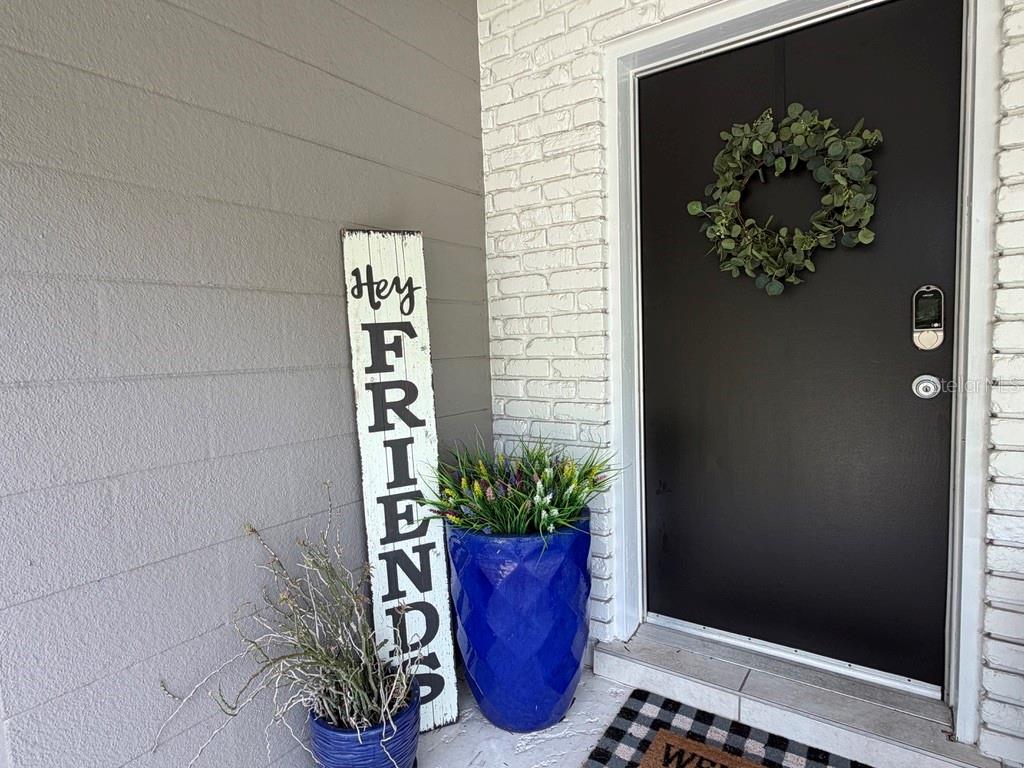 A front porch features a black door with a wreath, a sign, and two planters — 361 SCOTT AVENUE, SARASOTA, FL
