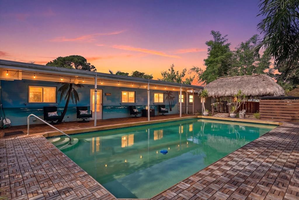 A swimming pool sits in front of a house with a mural and thatched-roof gazebo — 361 SCOTT AVENUE, SARASOTA, FL