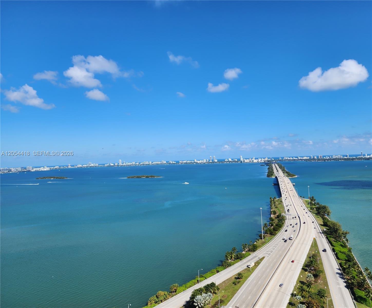An aerial view shows a long causeway bridge extending across a large body of water — 601 NE 36th St # 3210, Miami FL 33137, MIAMI, FL