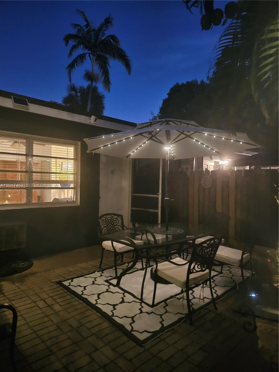 A patio features a dining set with an umbrella and string lights on a rug — 325 Fernwood Rd # 10, Key Biscayne FL 33149, KEY BISCAYNE, FL