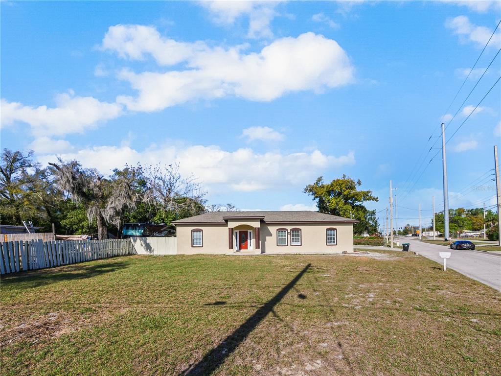 A single-story tan house with a red front door sits behind a large grassy yard — 4901 BALBOA DRIVE, ORLANDO, FL