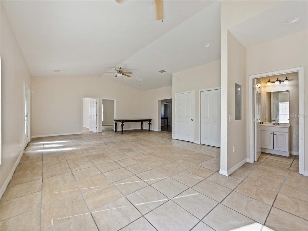 A spacious living area with beige tile flooring, vaulted ceilings, and multiple doorways — 4901 BALBOA DRIVE, ORLANDO, FL