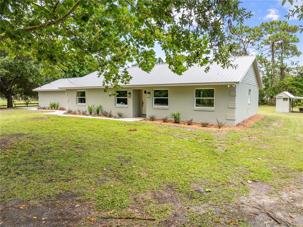 A single-story house with a light-colored exterior and metal roof sits on a grassy lot — 4279 HENRY J AVE, ST CLOUD, FL